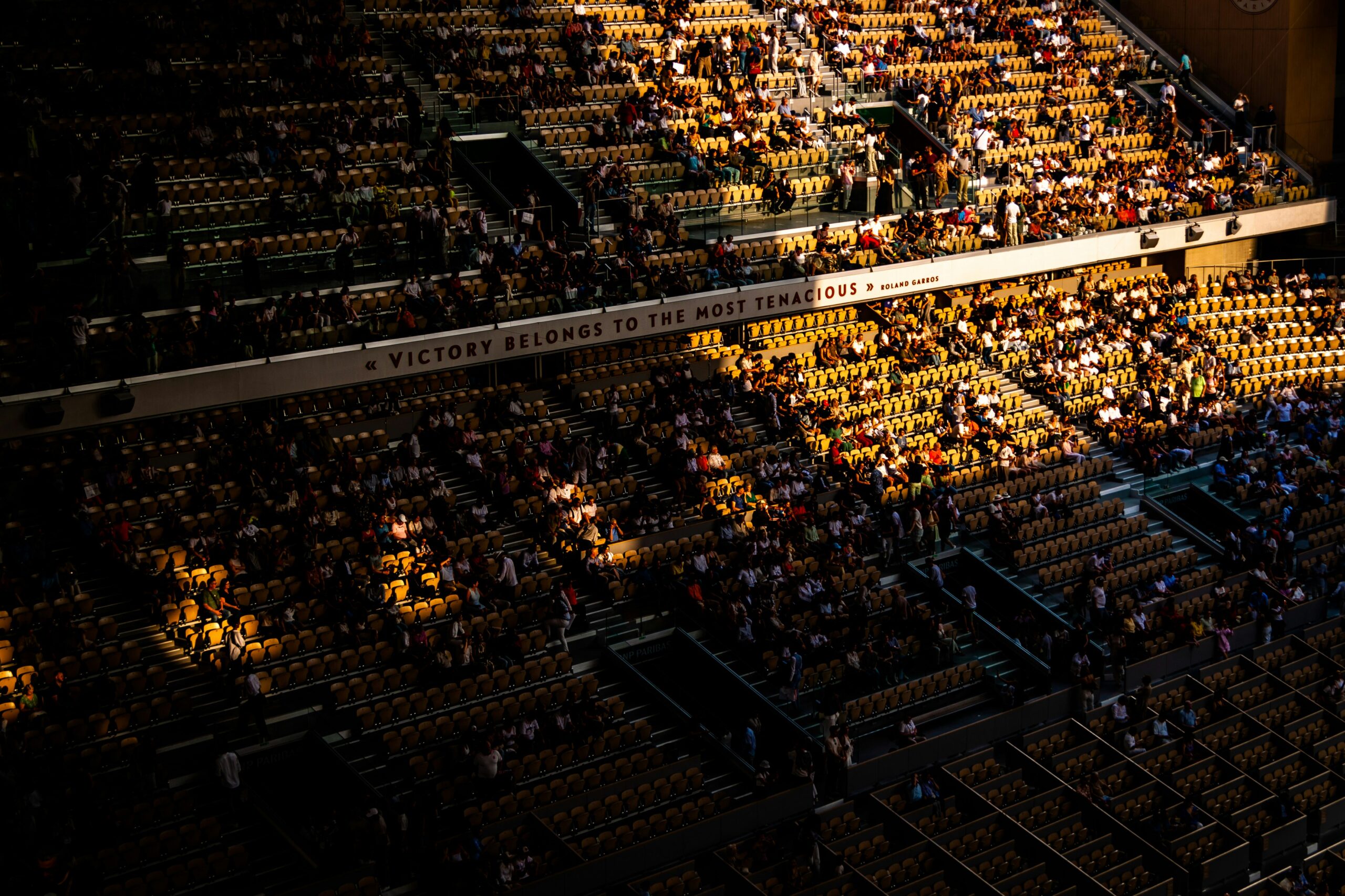 Aerial view of Roland Garros stadium seating with the quote Victory belongs to the most tenacious